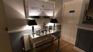 A modern living room with a glass coffee table, two lamps, a decorative clock, and a sign above the table reading "MOËT & CHANDON CHAMPAGNE". - The Ascott (Manchester)