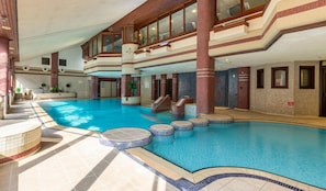 A large indoor swimming pool with multiple levels, a central staircase, and a tiled floor. - Whitewater Spa & Leisure Club (Ulverston)