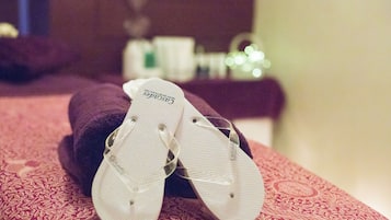 A pair of flip-flops on a patterned bedspread.