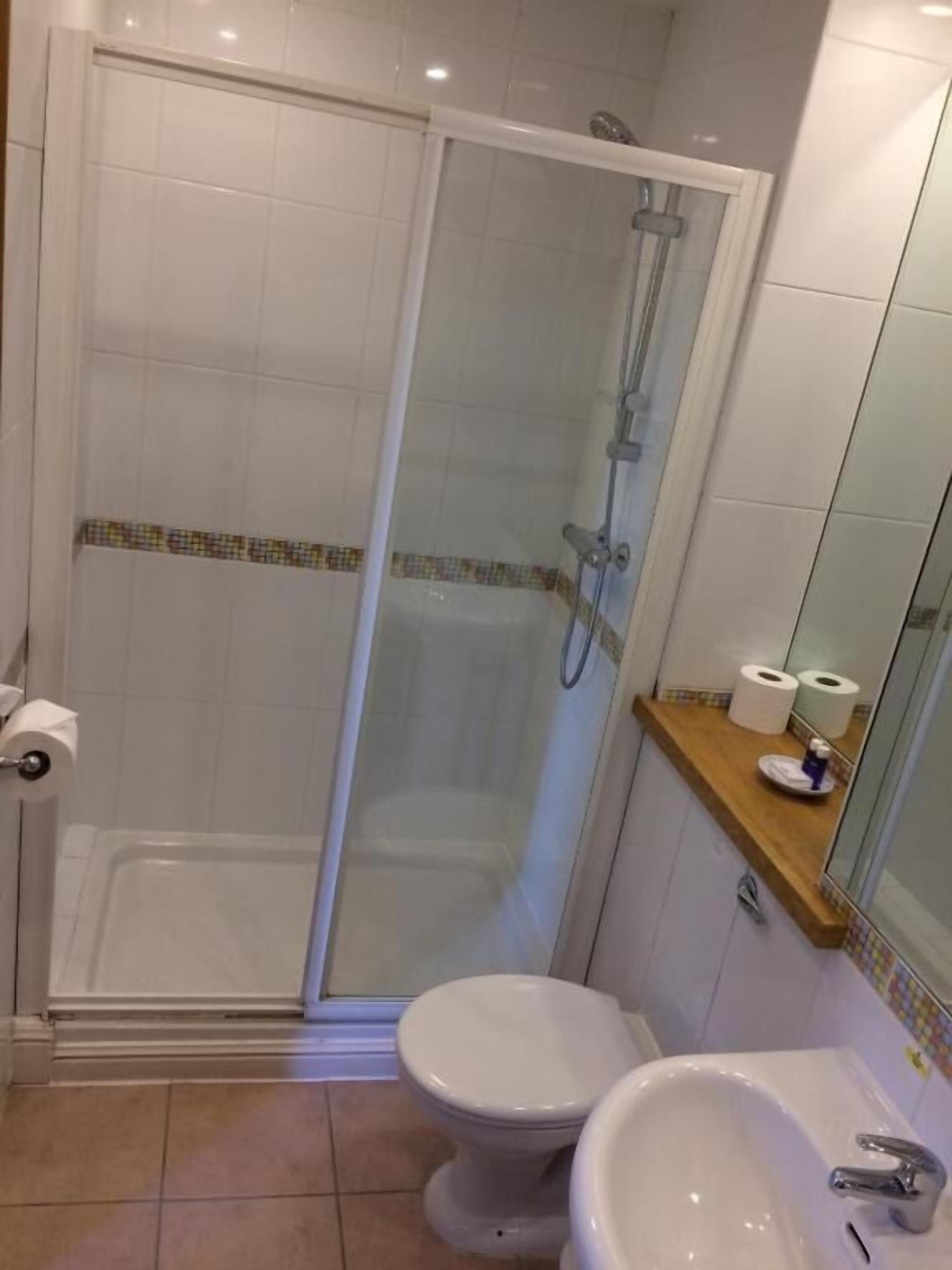 A bathroom with a glass-enclosed shower, a toilet, and a sink.