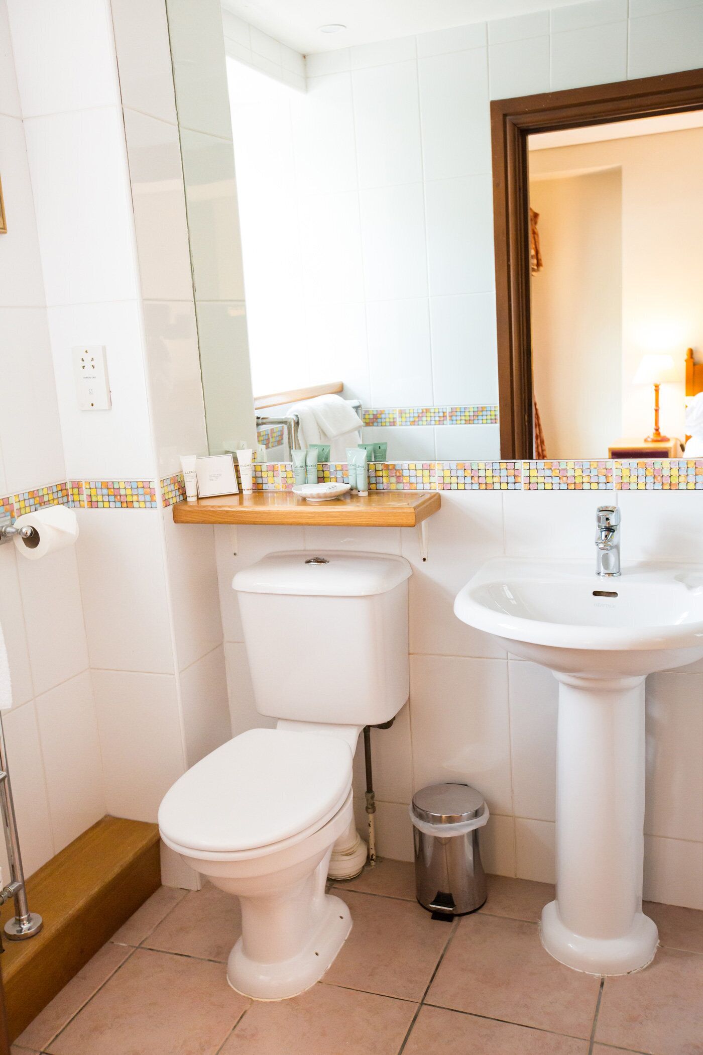 Une salle de bain avec des toilettes, un lavabo et une poubelle.