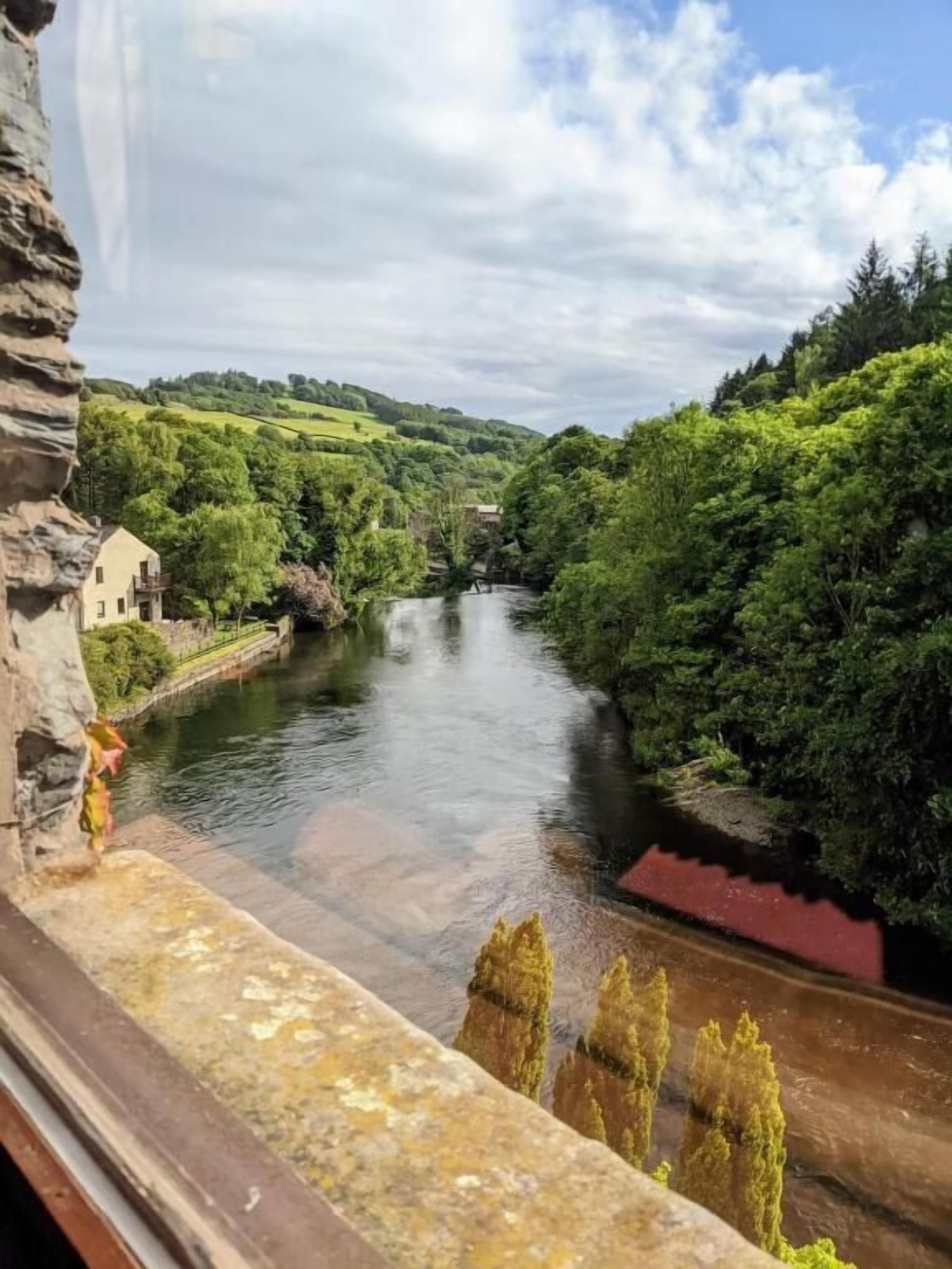 A river with a stone bridge and a building on the left.