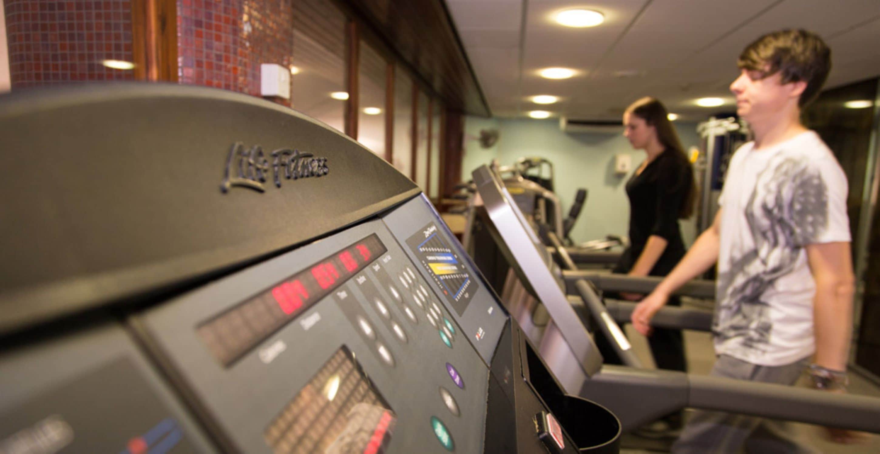 A gym with treadmills and a digital display.