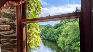 A window with a view of a river and greenery, a stone wall, and a wooden ledge. - Whitewater Spa & Leisure Club (Ulverston)