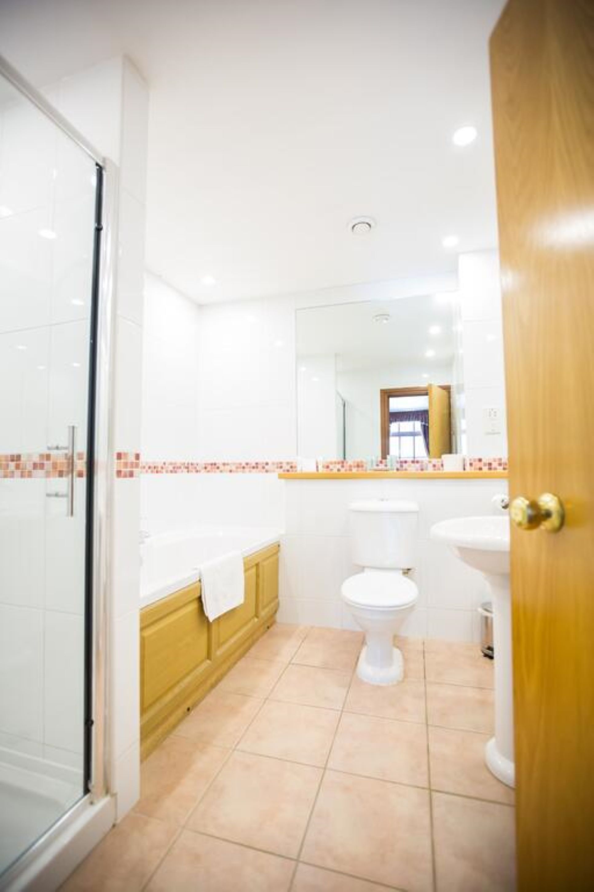 A bathroom with a glass shower enclosure, a bathtub, a toilet, and a sink.