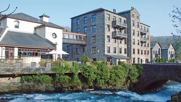 A stone bridge over a river with buildings on either side, including a white building with a clock and a stone building with balconies.