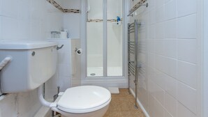 Et badeværelse med toilet, bruser og håndvask.