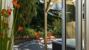 An outdoor patio area with two wooden chairs, a stone wall, and a wooden fence. - Grange Manor (Grange-over-Sands)