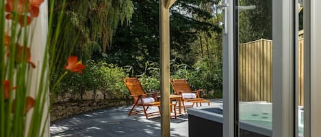 An outdoor patio area with two wooden chairs, a stone wall, and a wooden fence.