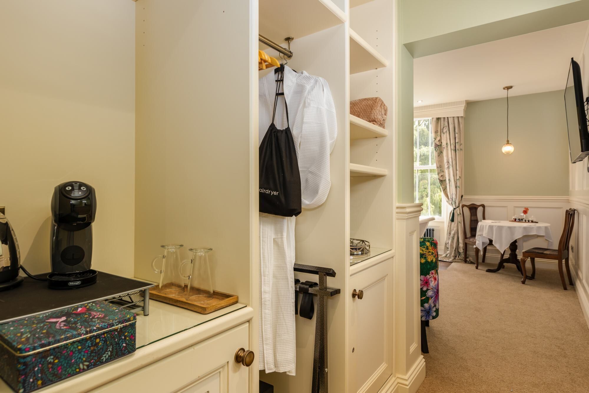 A hotel room with a kitchenette, a dining area, and a bathroom.