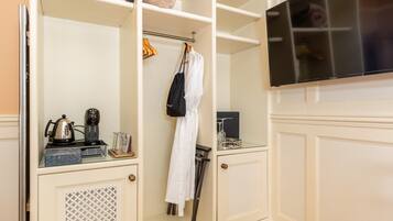 Habitación de hotel con minibar, cafetera, secador de pelo y televisor.