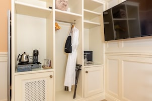 Habitación de hotel con minibar, cafetera, secador de pelo y televisor.