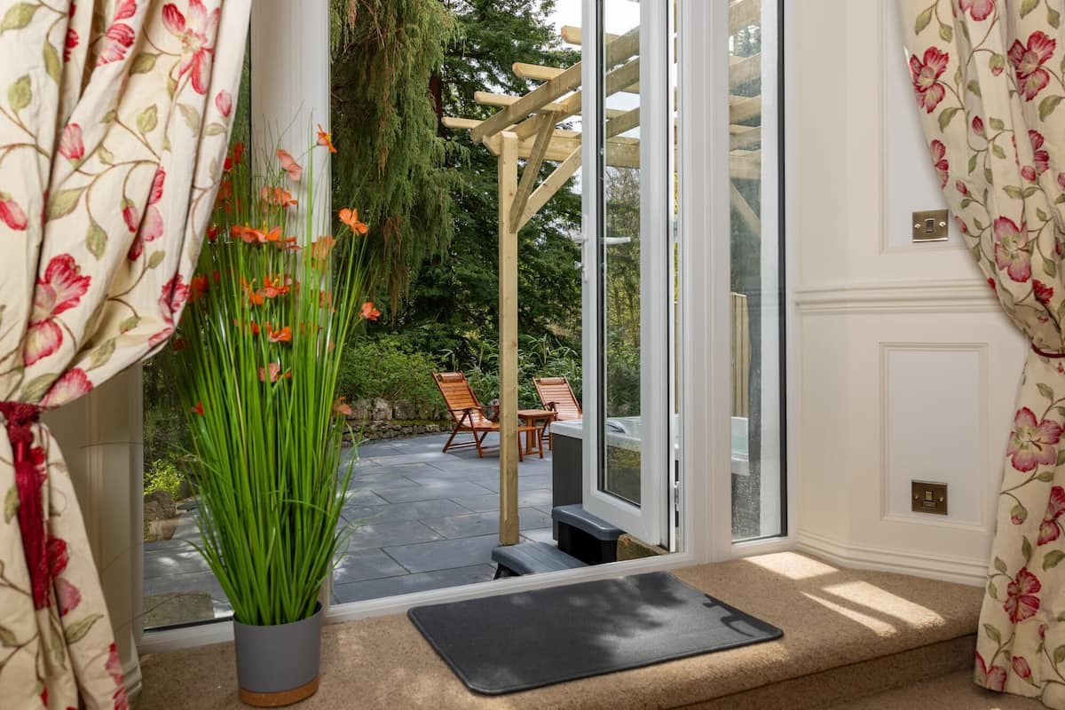 Une pièce donnant sur un jardin grâce à une porte vitrée, avec une chaise en bois et une plante en pot.