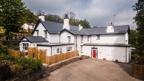 A white building with a red door, a stone wall, and a wooden fence. - Grange Manor (Grange-over-Sands)
