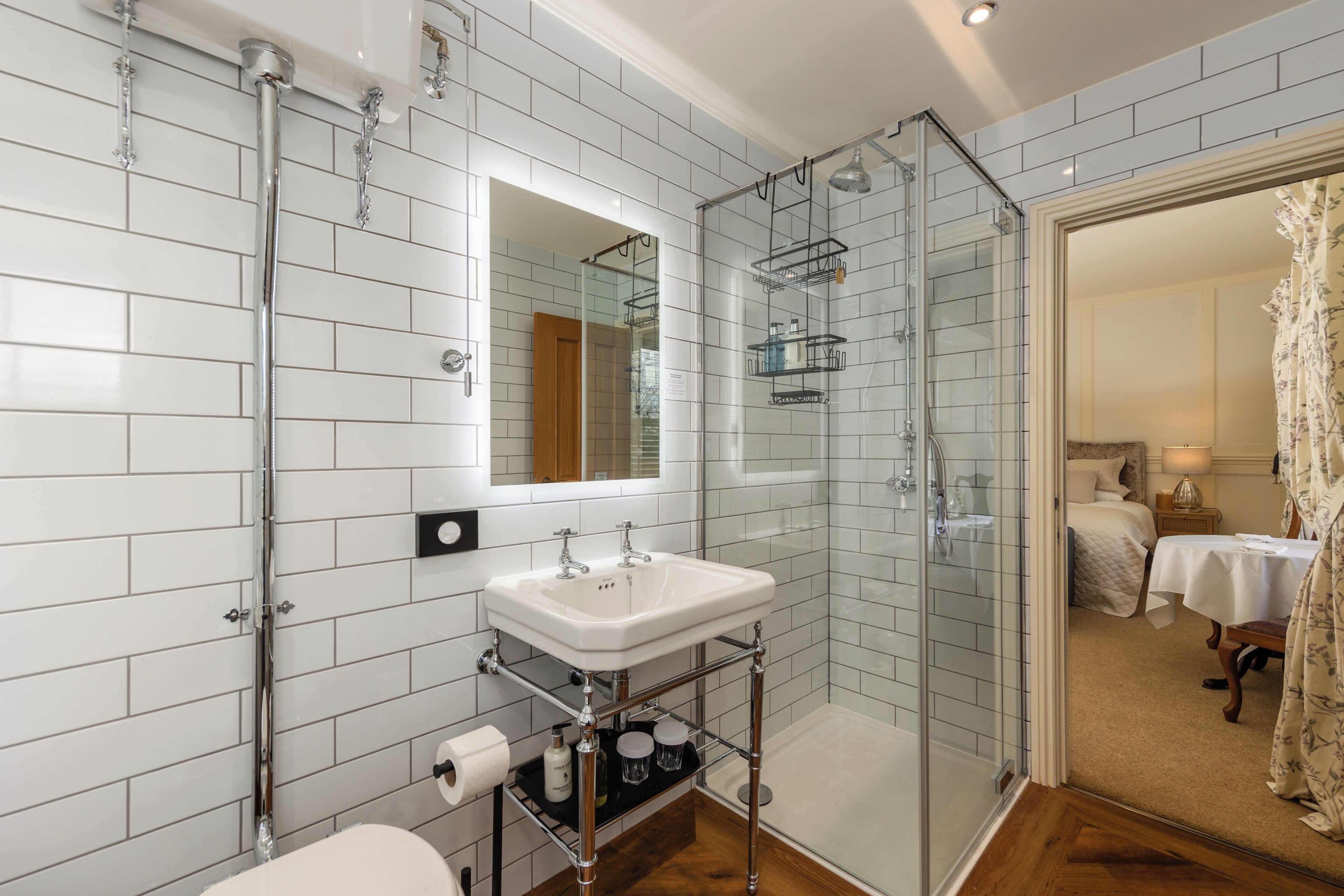 Un baño moderno con cabina de ducha de vidrio, un lavabo blanco con espejo y una puerta de madera.