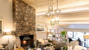 Un espacio lounge acogedor con chimenea de piedra, asientos cómodos y vistas al exterior.