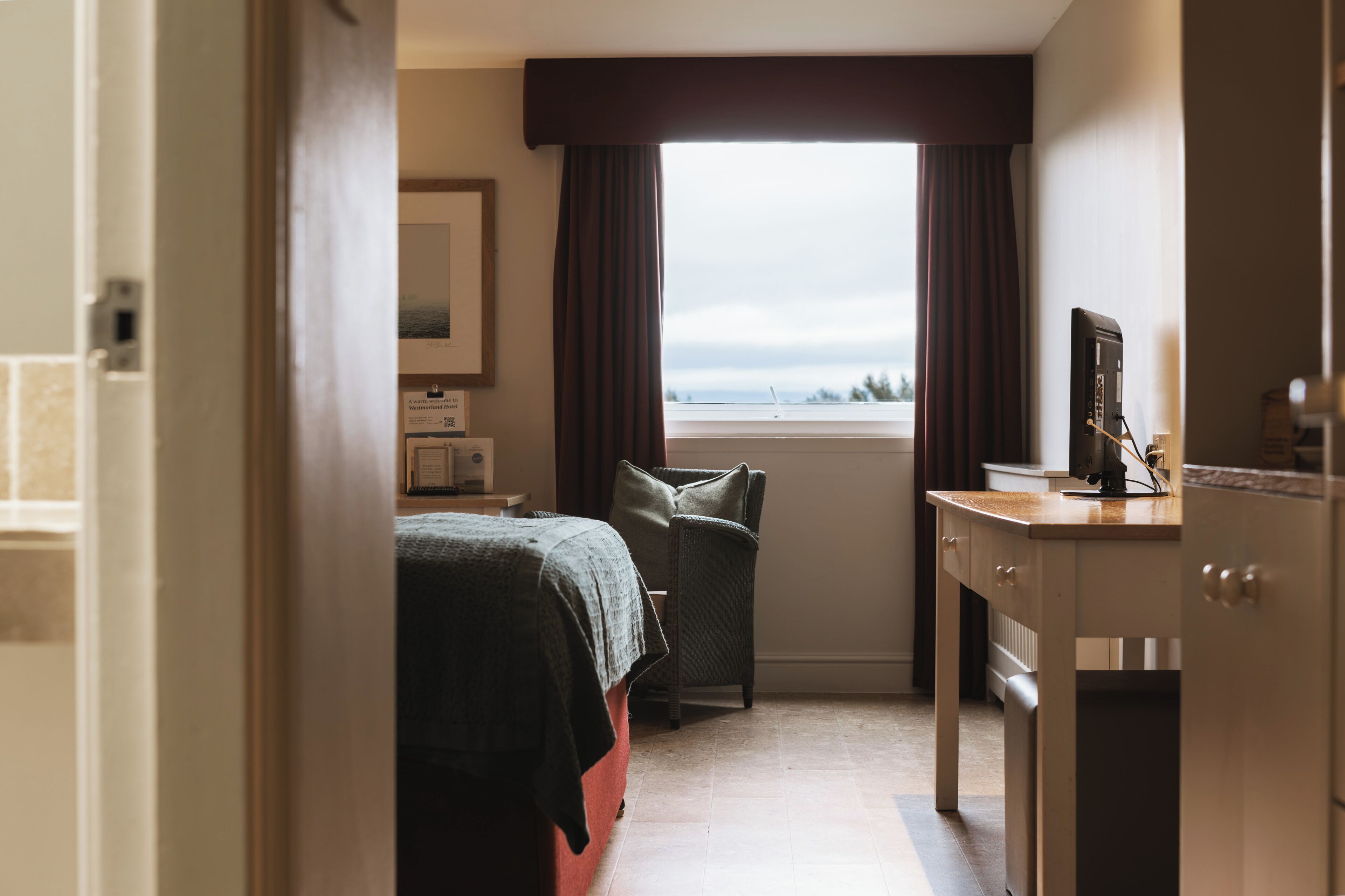 Een hotelkamer met een bed, bureau, stoel en raam met uitzicht.