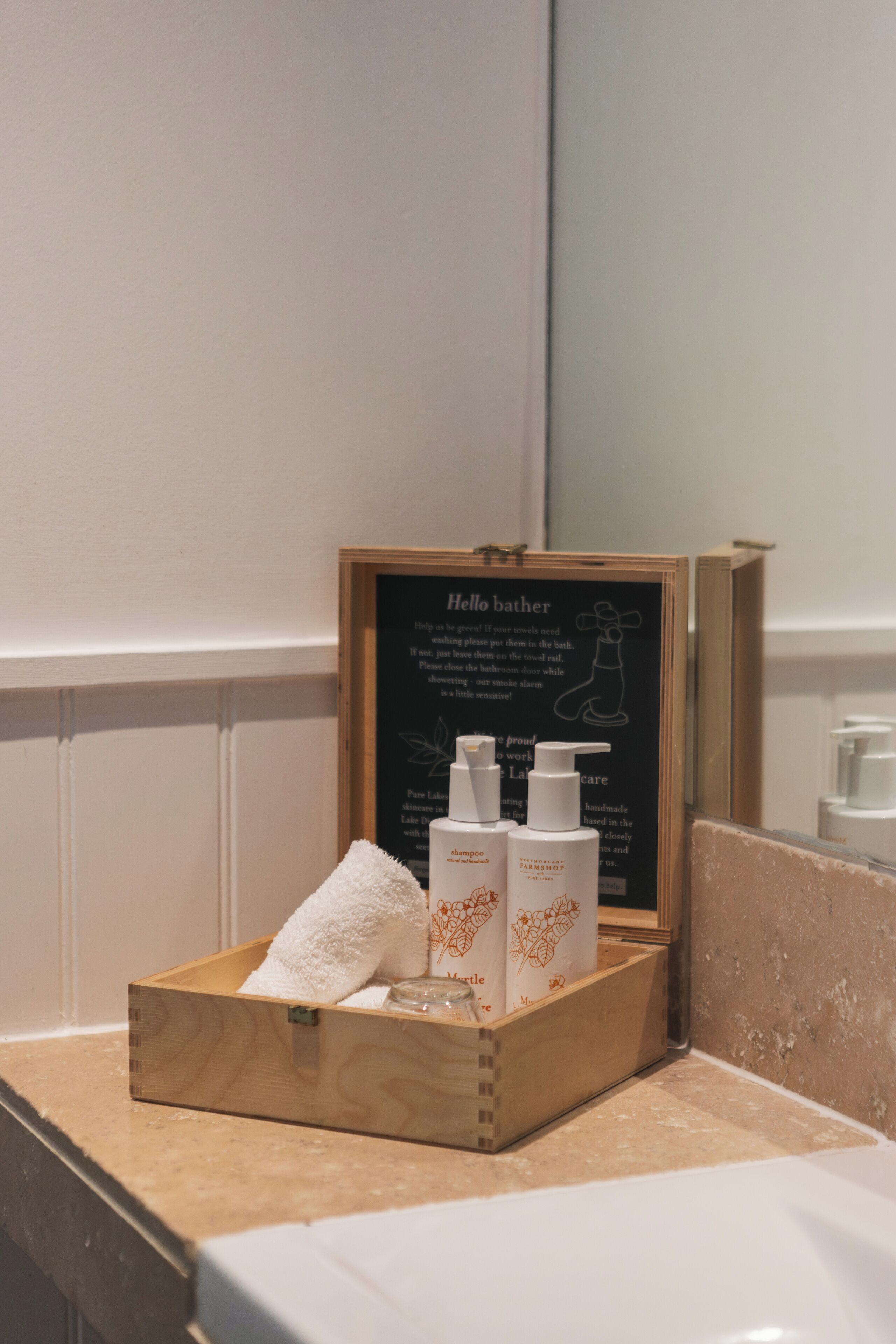 Une boîte en bois contenant des articles de toilette, posée sur le comptoir d’une salle de bain.