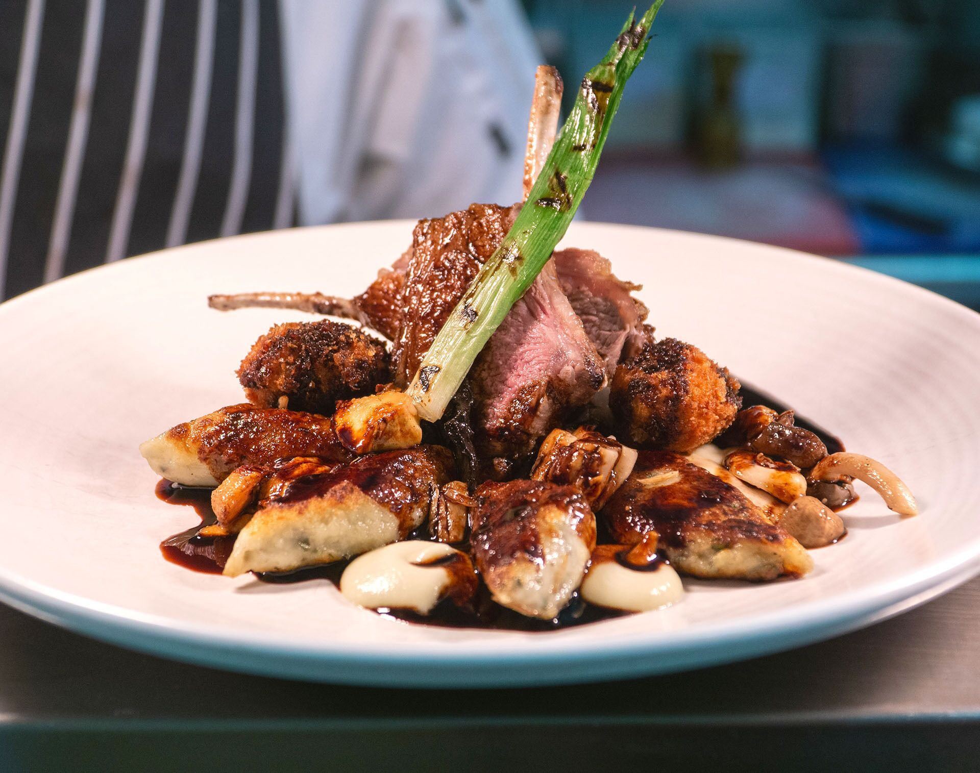 A plate of food with a piece of meat, mushrooms, and a green vegetable garnish.