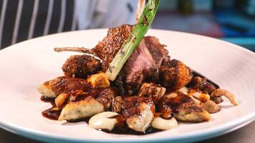 A plate of food with a piece of meat, mushrooms, and a green vegetable garnish.