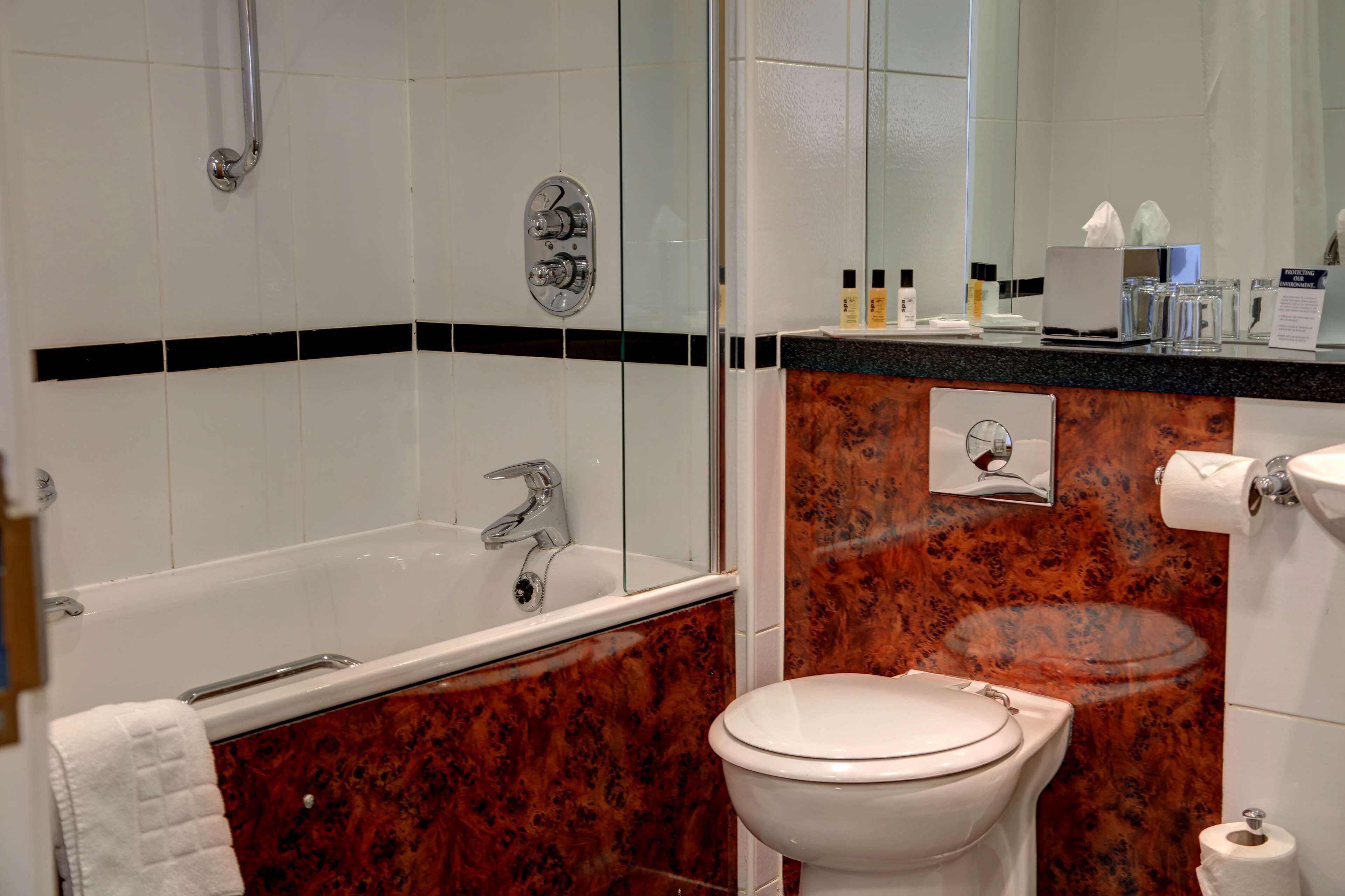 Un baño con bañera, inodoro y tocador con espejo.