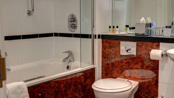 Un baño con bañera, inodoro y tocador con espejo.
