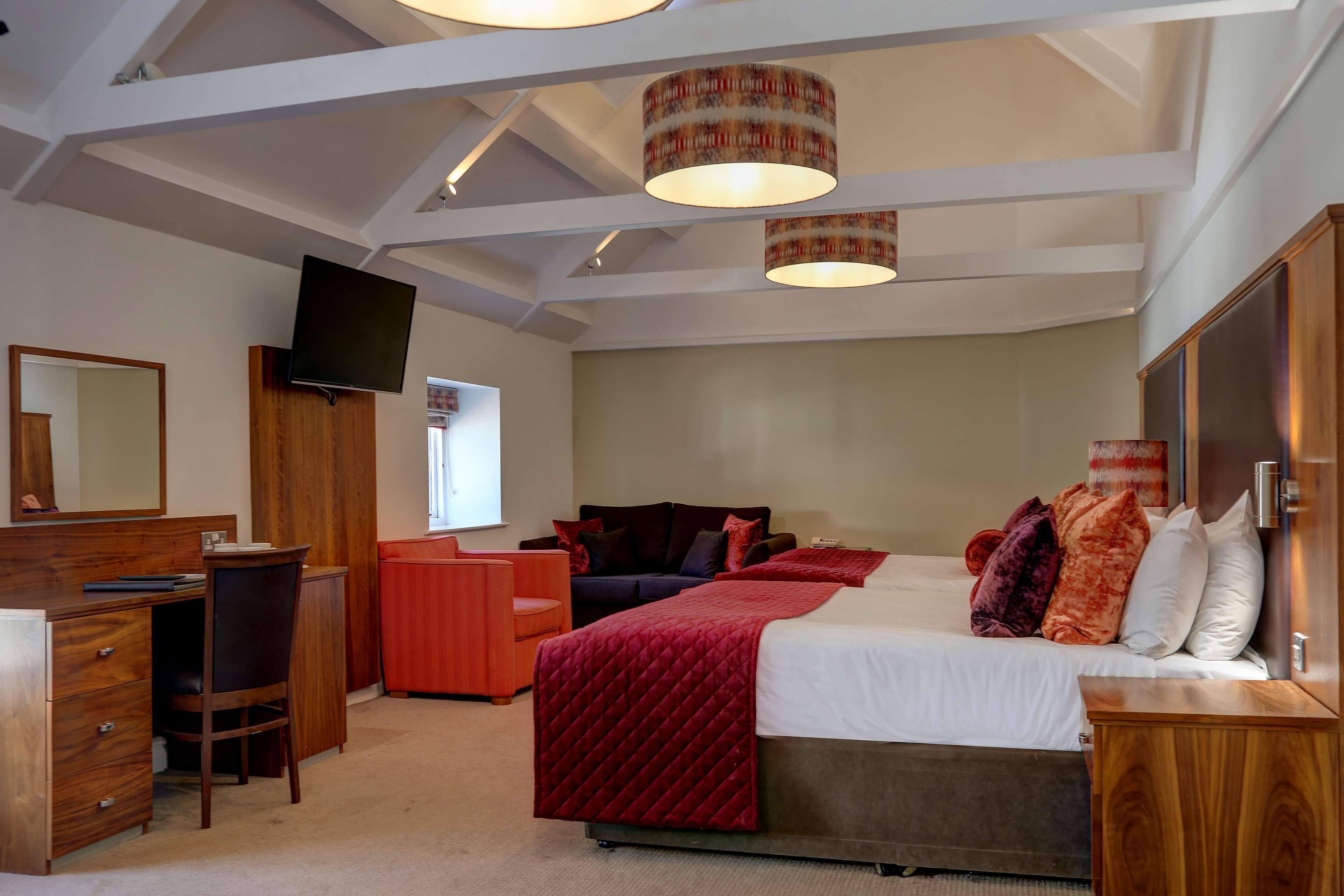 Een slaapkamer met een bed, bureau, stoel en een televisie aan de muur.