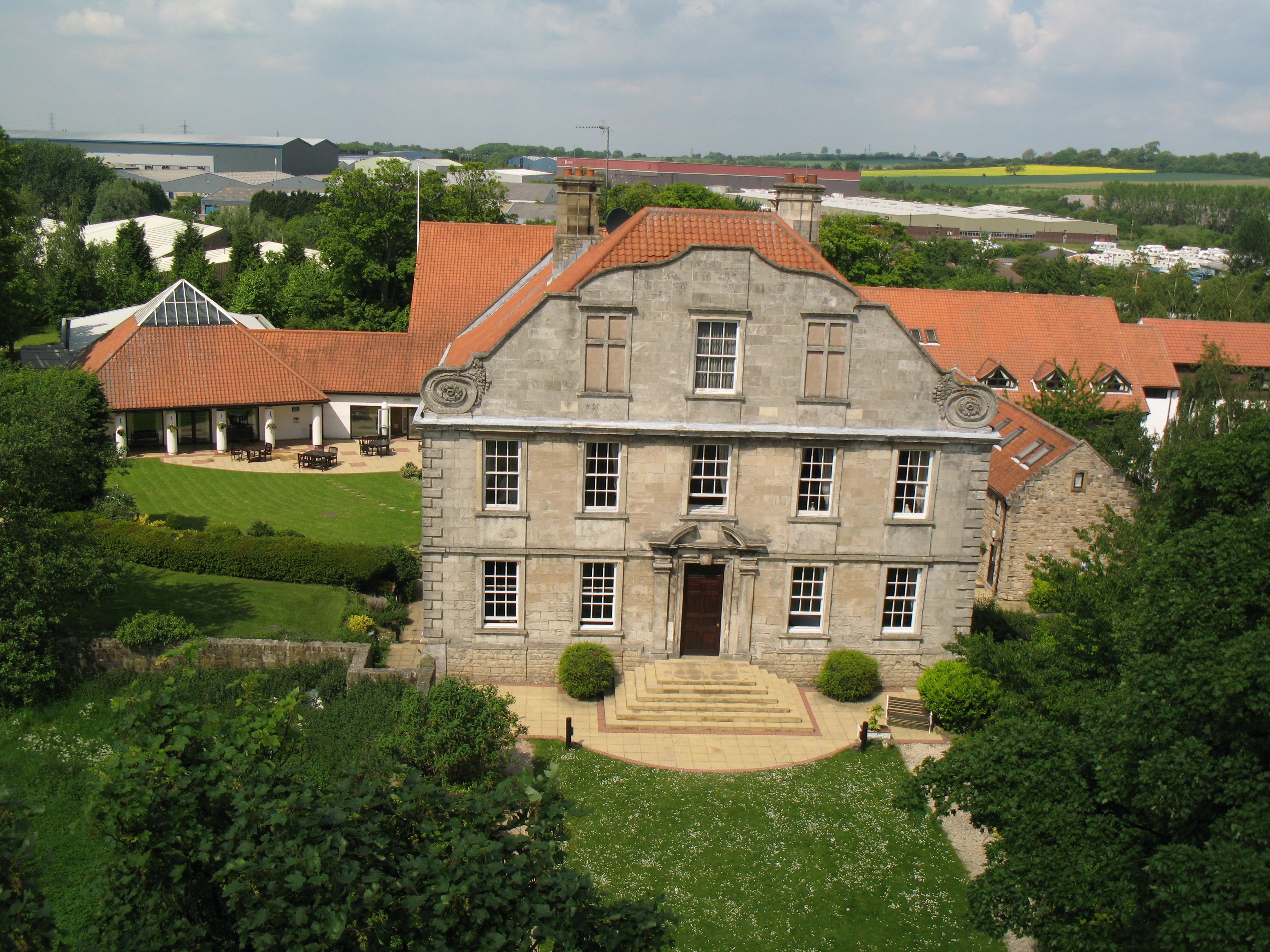 A large stone building with a symmetrical facade, multiple windows, and a central entrance.