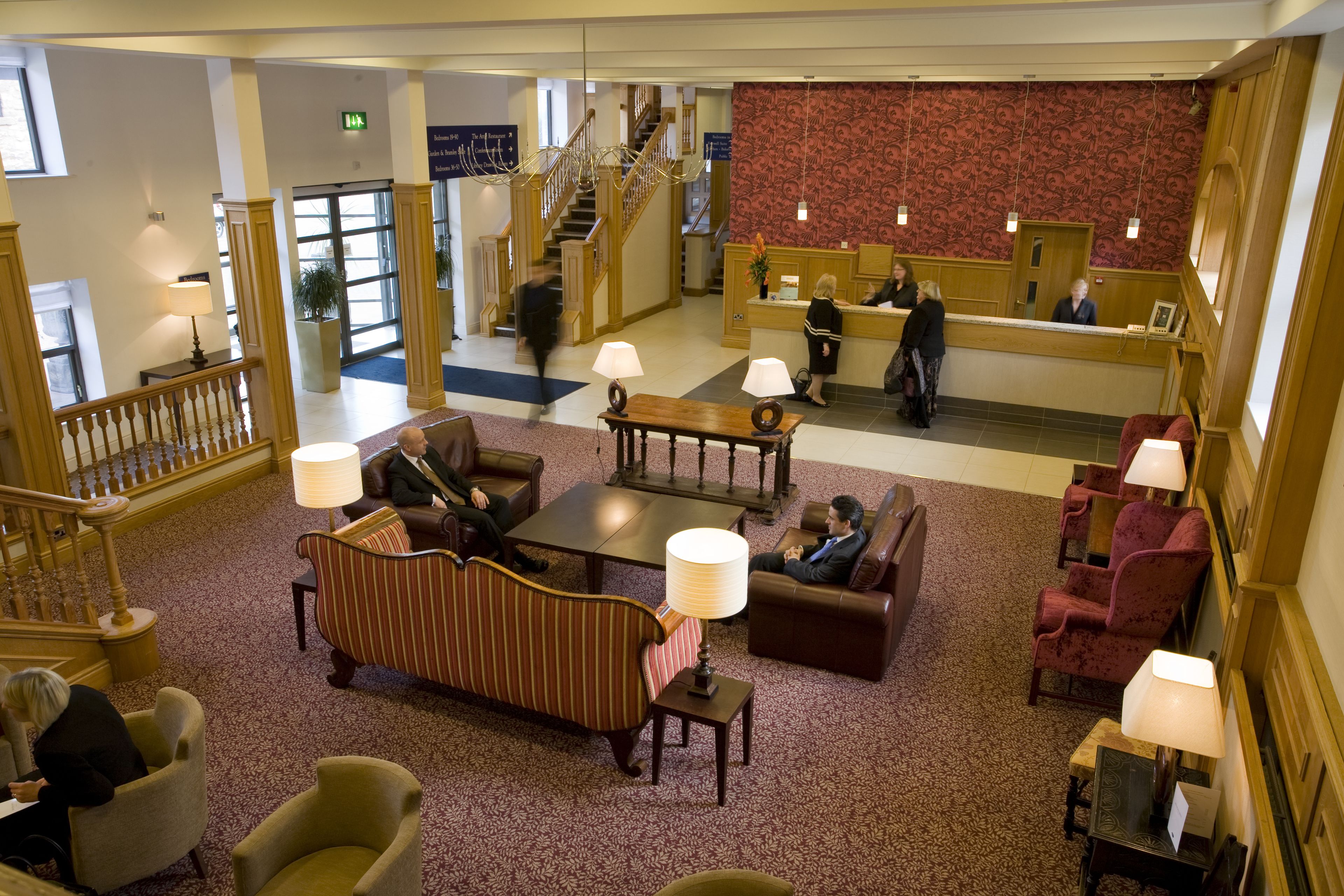 A spacious lobby with a reception desk, comfortable seating areas, and a staircase leading to upper floors.