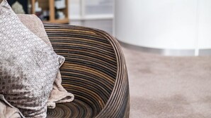 A modern living room with a round, textured sofa, a wooden bookshelf, and a white reception desk. - Hellaby Hall Hotel, BW Signature Collection (Rotherham)