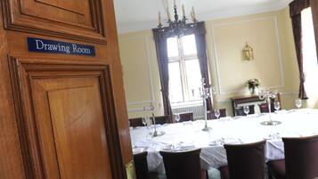 A dining room with a table set for six, a chandelier, and a window with curtains.