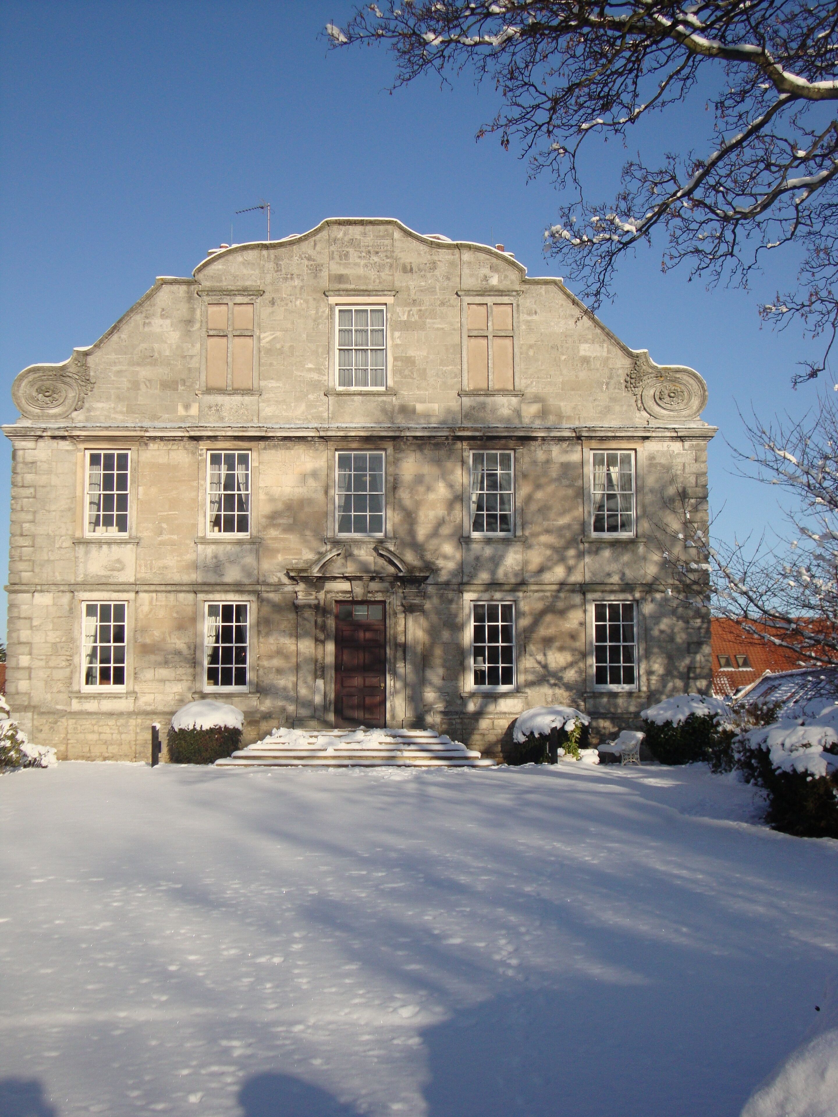 A large, historic stone building with a symmetrical facade, multiple windows, and a central entrance.