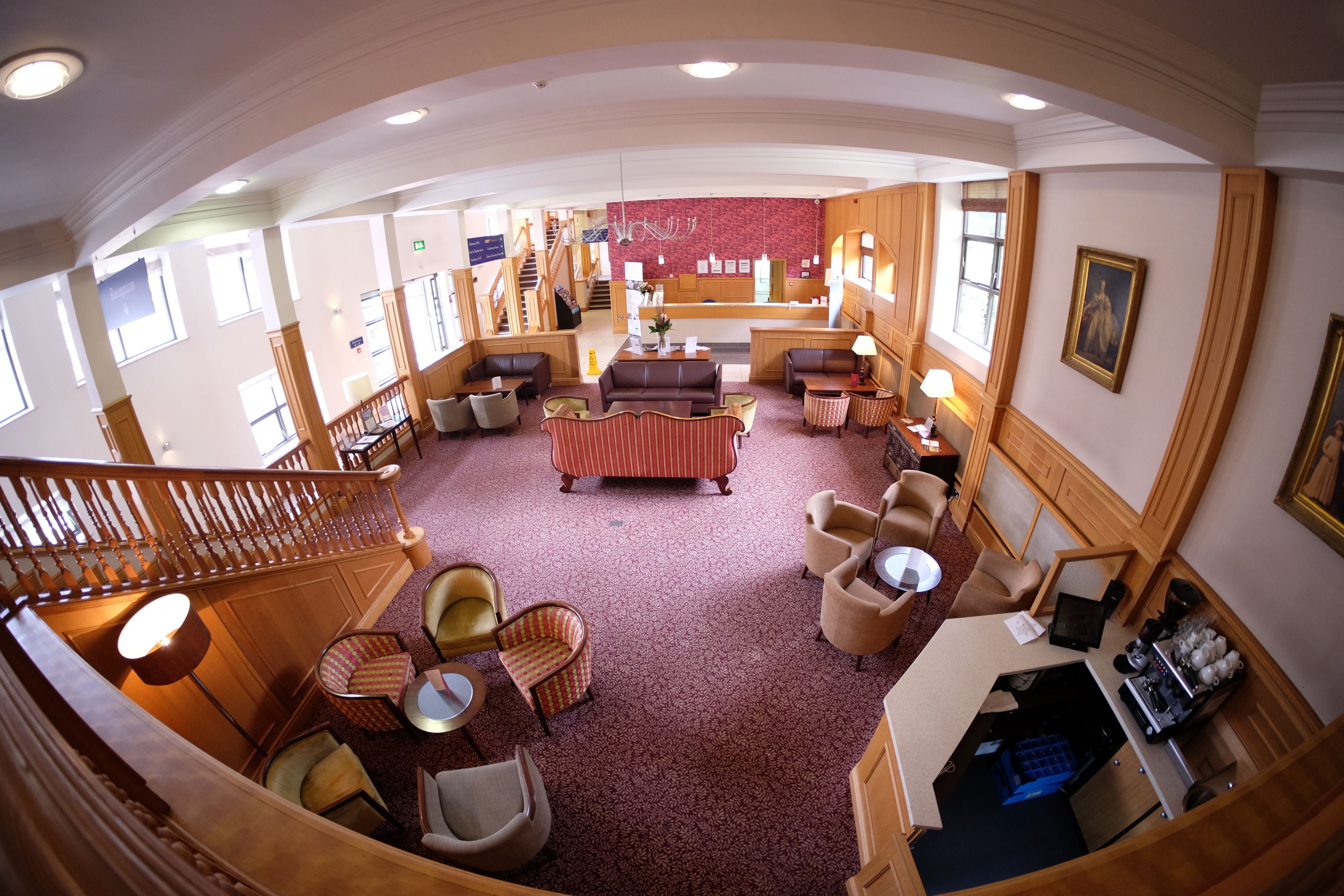 A spacious lobby with a high ceiling, a staircase, and a reception desk.