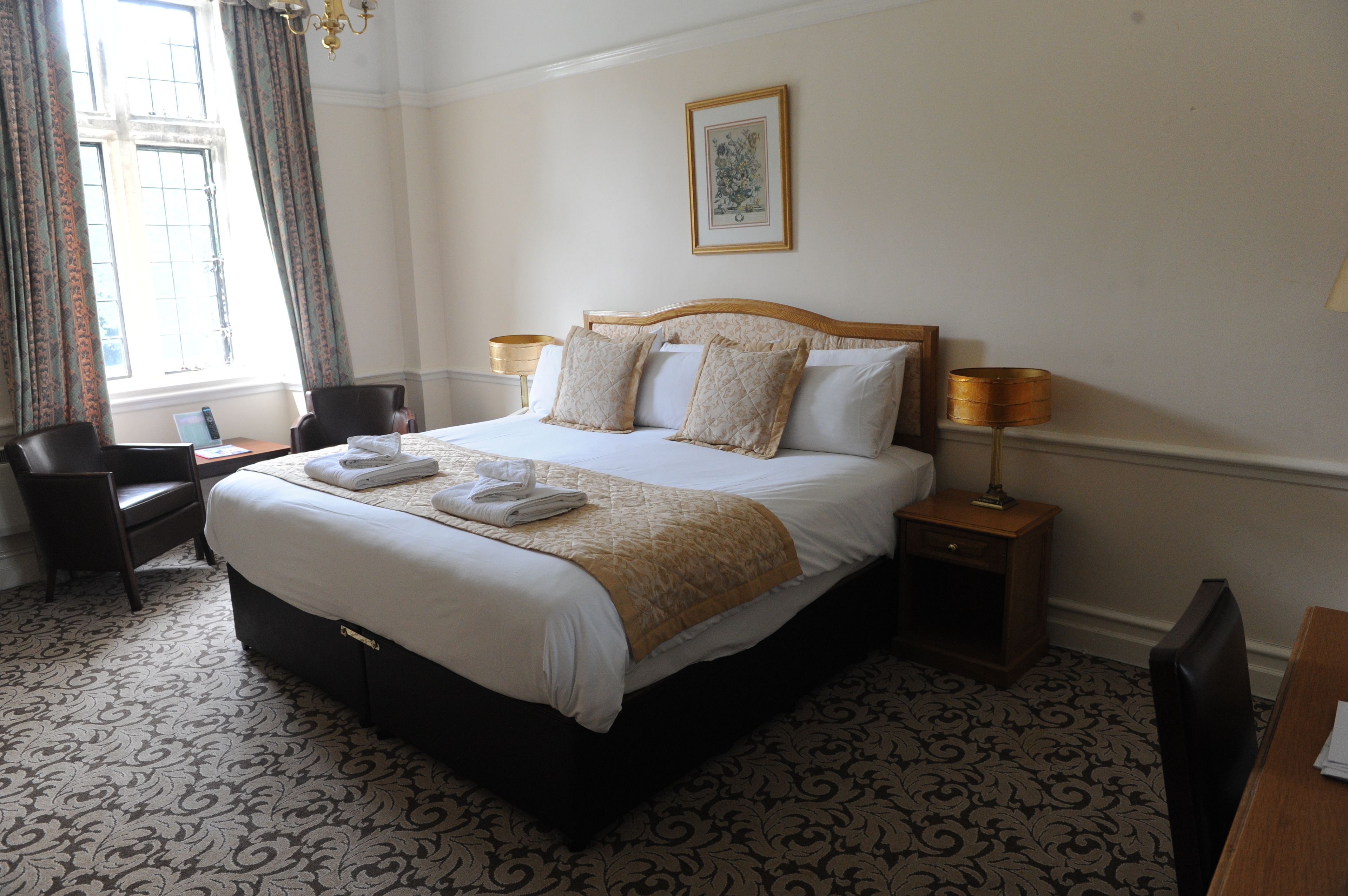 A neatly made bed with a duvet, two pillows, and a bedside table with a lamp.