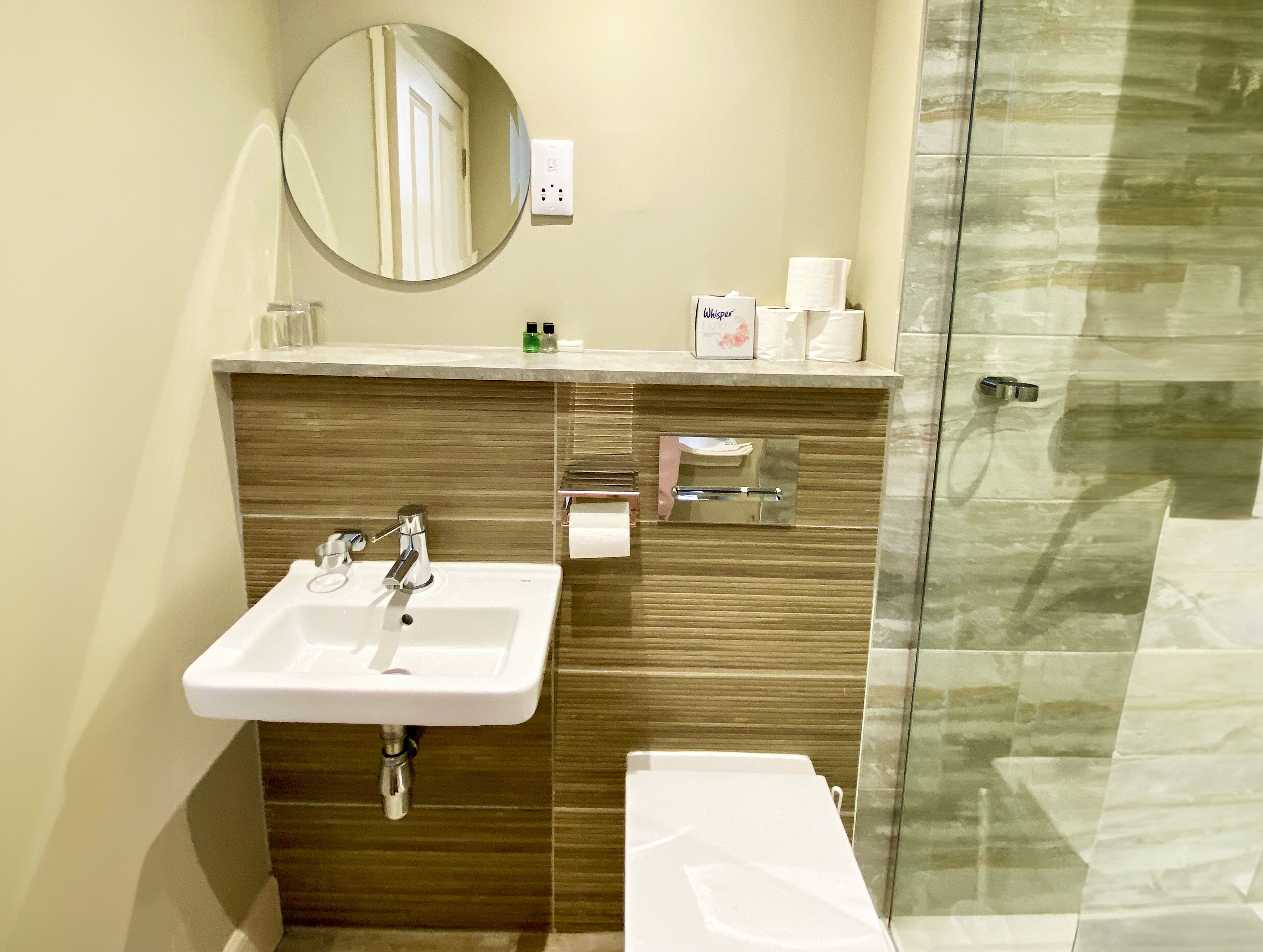 A modern bathroom with a sink, mirror, and glass shower enclosure.