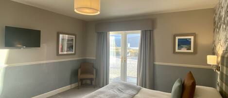 A hotel room with a bed, a chair, a television, and a window with curtains.