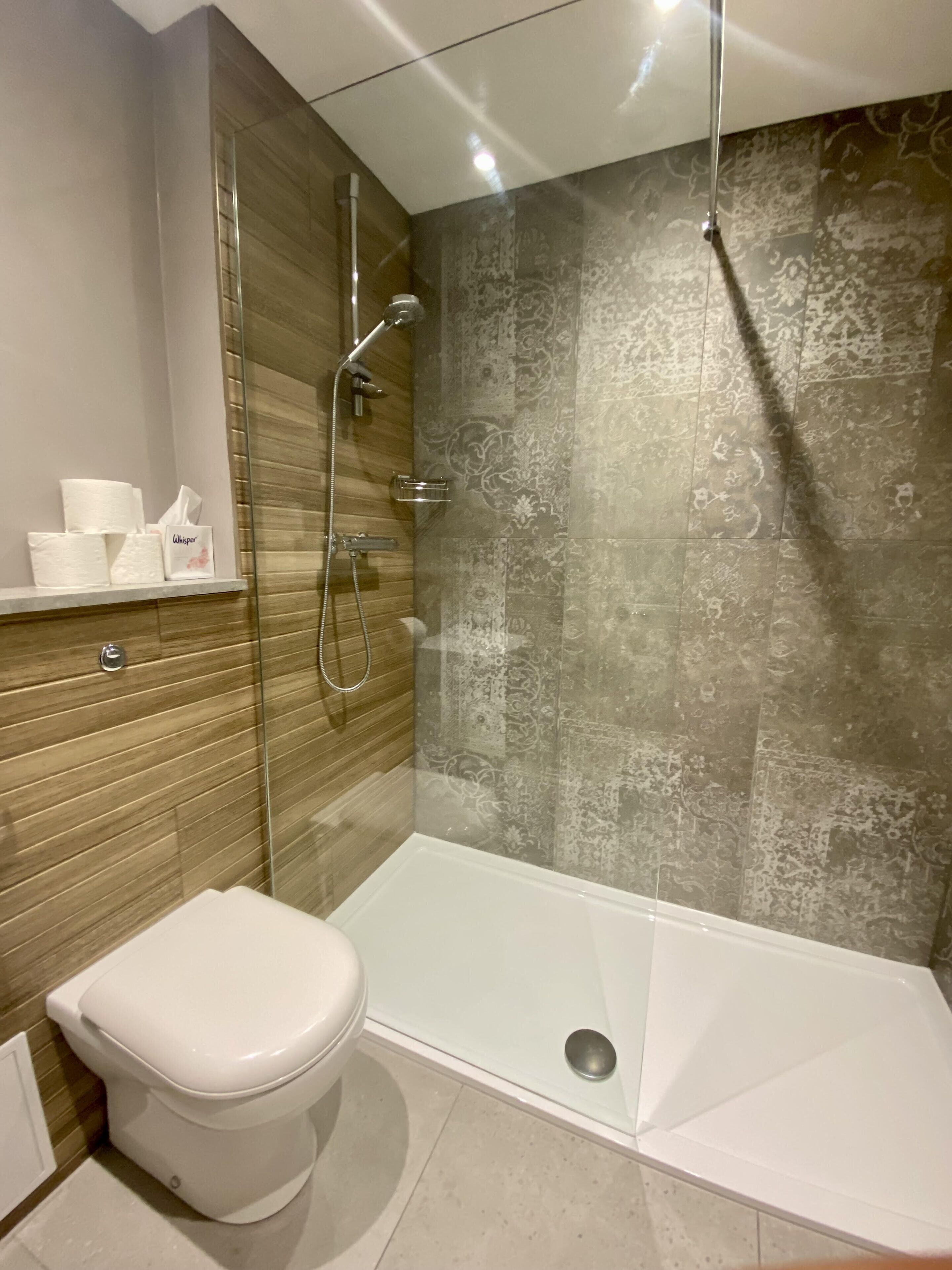 Ein modernes Badezimmer mit einer Duschkabine, einer Toilette und einer Badewanne.