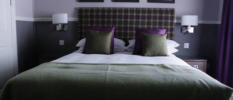 A hotel room with a large bed, two bedside lamps, and three framed pictures on the wall.