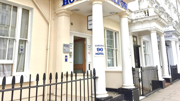Un edificio con un cartel que dice "HOTEL CARLTON" y una puerta con la etiqueta "90 HOTEL".