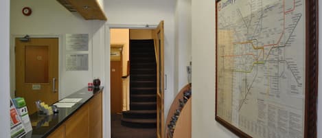 A hallway with a reception desk, a staircase, and a large map on the wall.