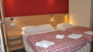 Habitación de hotel con dos camas, paredes rojas y cabecero de madera.