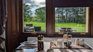 Een eettafel met uitzicht op een grasveld en bomen door een raam.