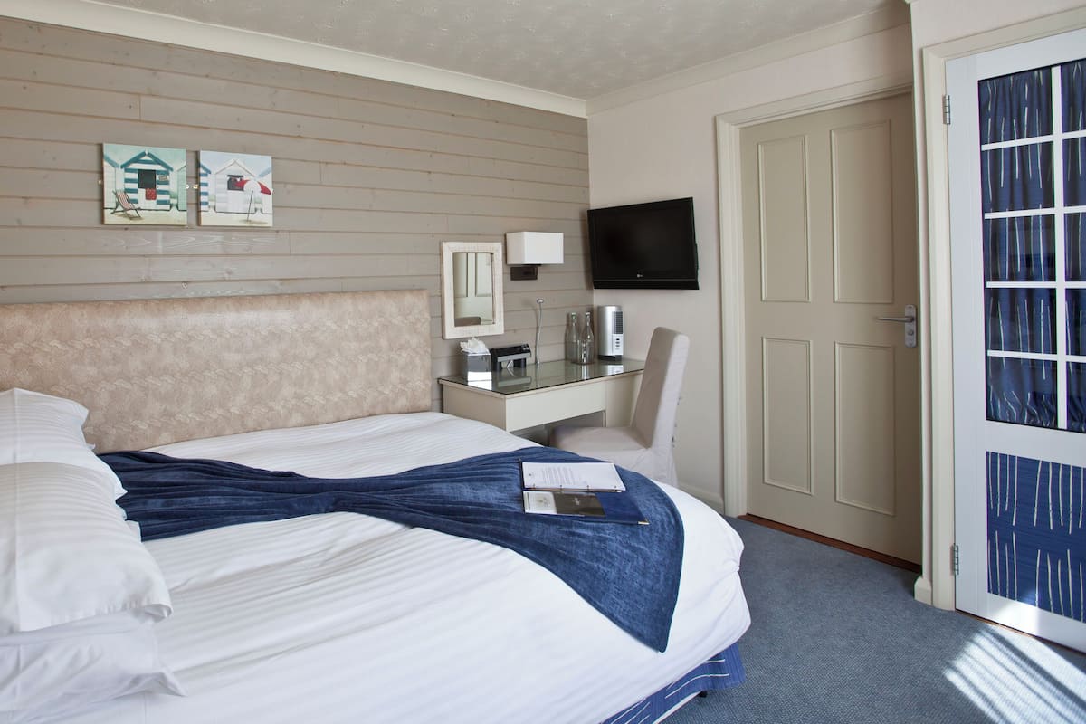 Une chambre d’hôtel avec un lit, une table de chevet, une télévision et une porte avec une fenêtre.