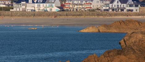A coastal town with stone buildings, a sandy beach, and rocky outcrops.