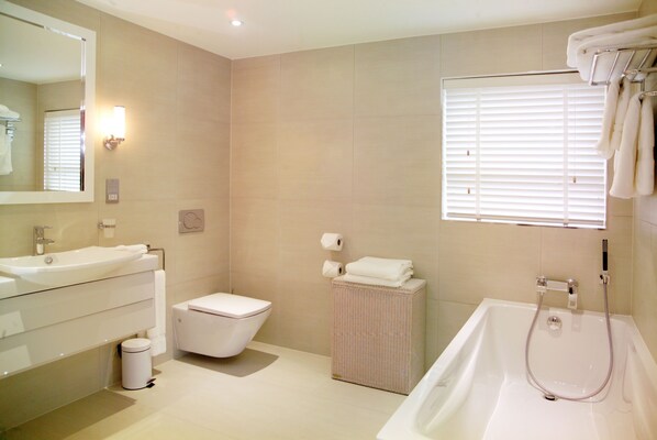 A modern bathroom with a sink, toilet, and bathtub. - Hotel La Place (St. Brelade)