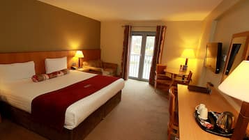 A hotel room with a large bed, a desk, a chair, a dining table, and a balcony with curtains.