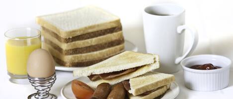 Una mesa de desayuno con una pila de sándwiches, un vaso de zumo de naranja, un huevo cocido, una taza de café y un recipiente pequeño de mermelada.