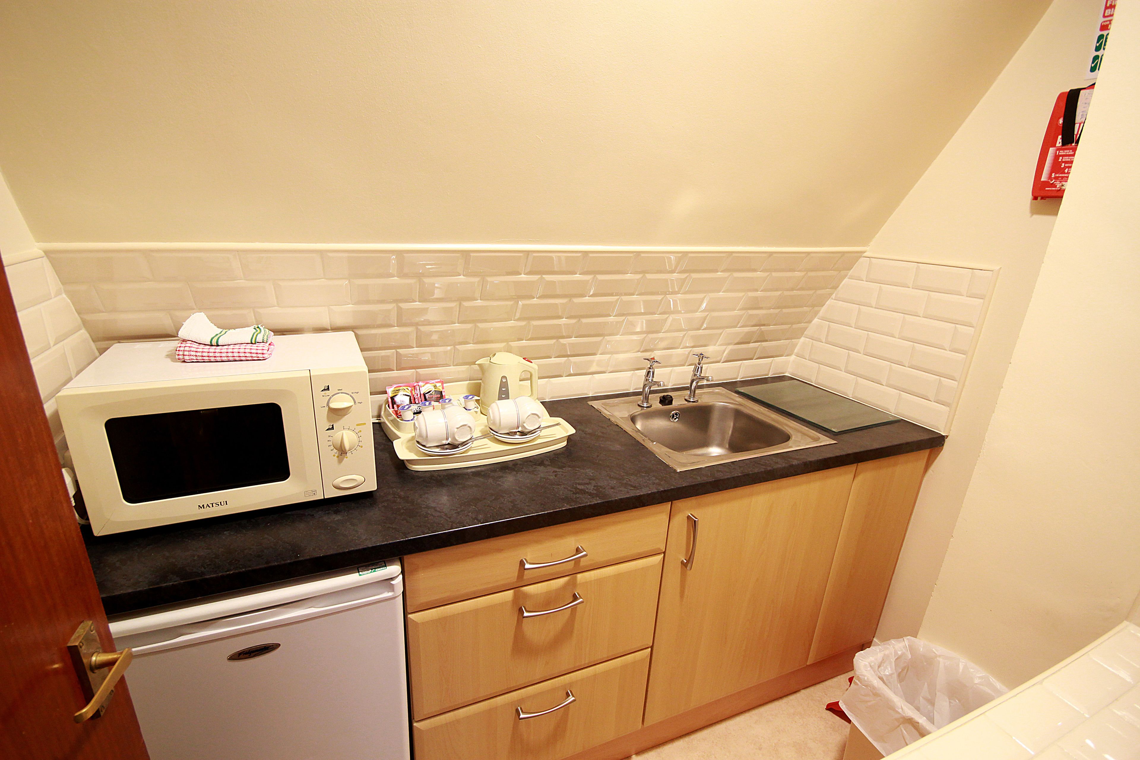 A compact kitchen with a microwave, toaster, and sink.