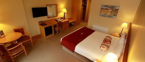 Una habitación de hotel con cama, escritorio, silla y televisión.