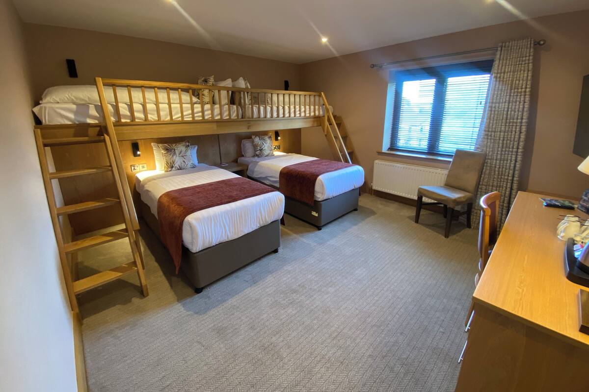 Ein Schlafzimmer mit Etagenbetten, einem Schreibtisch und einem Stuhl.